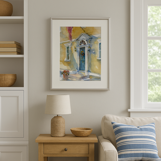 Framed painting on a wall above a side table with a lamp and decorative items, in a room with a couch and window.