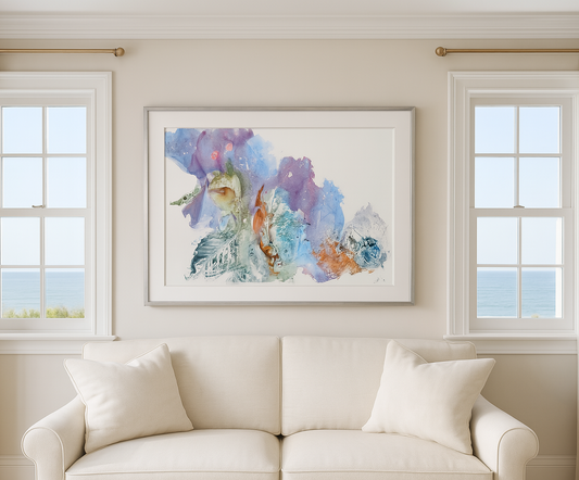 Framed abstract artwork on a wall above a beige sofa with large windows in the background.