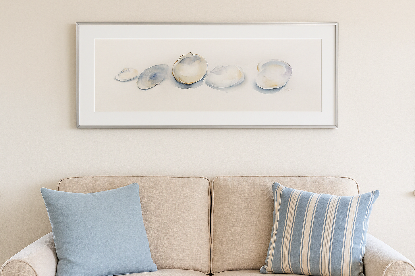 Framed artwork above a beige sofa with blue and striped cushions.