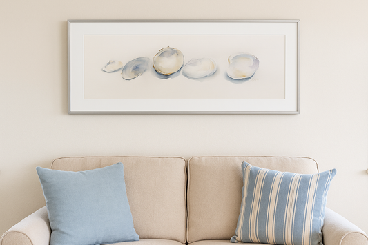 Framed artwork above a beige sofa with blue and striped cushions.